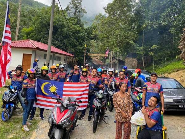 Muhammad Azamirudin (berkerusi roda) menyampaikan sumbangan kepada penduduk di perkampungan orang-orang asli Kuala Mu, Perak.