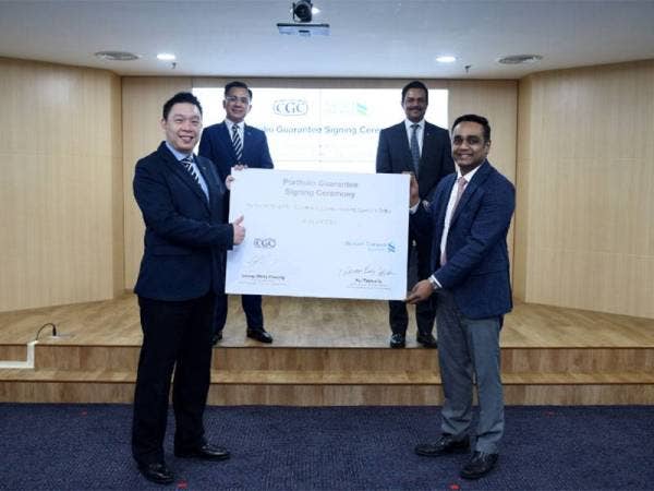 Weng Choong (kiri) dan Raj menunjukkan dokumen perjanjian antara Standard Chartered dengan CGC pada majlis kerjasama kedua-dua pihak di Kuala Lumpur sambil disaksikan oleh Mohd Zamree (kiri di belakang) dan Abrar.