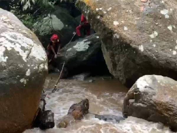 Anggota JBPM berusaha mengeluarkan mayat mangsa yang ditemui di celah batu.