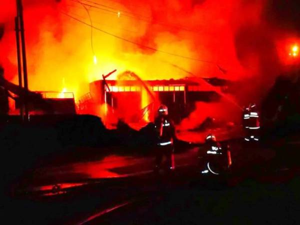 Anggota bomba sedang berusaha memadamkan kebakaran membabitkan kedai membaiki motosikal dan baik pulih pendingin hawa kereta terbakar.