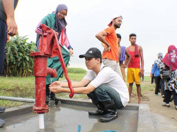Seorang pelajar perubatan UC menguji telaga tiub yang baru dibina sebagai sebahagian daripada misi mereka di Bangladesh pada tahun 2018.