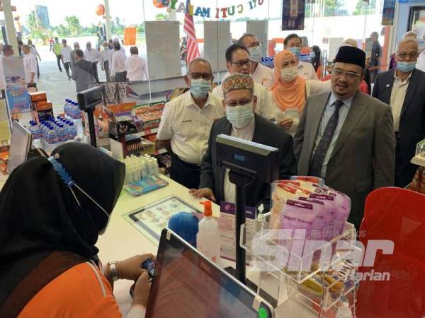 Mohd Amar (dua dari kanan) mencuba sistem pengisian di pam di BHPetrol Tunjong, hari ini.