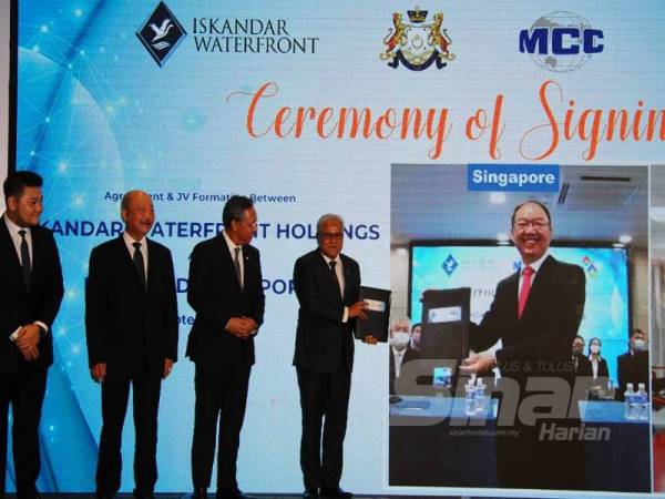 Pengarah Iskandar Waterfront Holdings, Datuk Mohd Noorazam Osman (empat dari kiri) dan Ketua Pegawai Eksekutif MCC Singapura, Tan Zhiyong (kanan) disaksikan Hasni (tiga kanan) menunjukkan dokumen perjanjian dalam satu persidangan video menerusi Majlis Memeterai Perjanjian antara Iskandar Waterfront Holdings dan Metallurgical Corporation of China Bhd di Hotel Double Tree Hilton, Johor Bahru, hari ini.