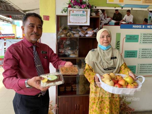 Shamsul (kiri) bersama Norihan menunjukkan bekalan makanan yang disediakan di dalam Gerobok Rezeki SMK Kota. 