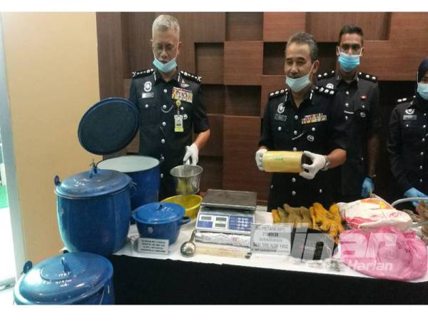 Hasanuddin (kiri) dan Adzli (kanan) menunjukkan sebahagian peralatan memproses dadah dirampas di sebuah rumah di Padang Temusu, Sungai Pasir, Sungai Petani kelmarin.