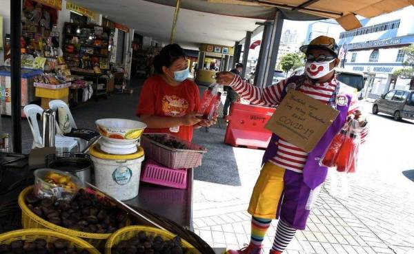  Lengkap berpakaian sut badut, Yusmanizam Hassan menghiburkan orang ramai di Pasar Chowrasta Pulau Pinang di sini sambil menjual air serbat yang dibuatnya sendiri untuk menjana pendapatan.