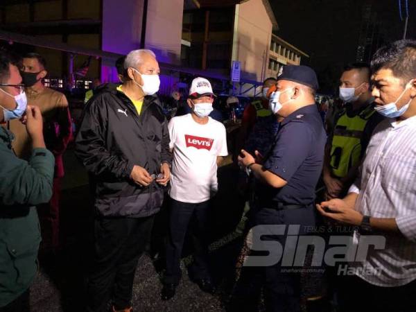 Annuar (kiri) diberikan penerangan serba sedikit situasi semasa banjir kilat oleh petugas di lokasi. 