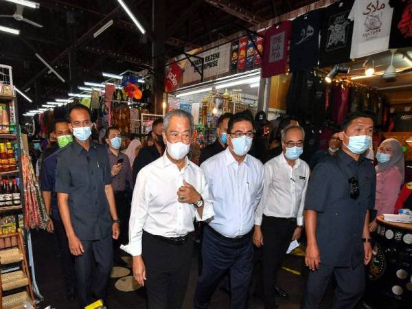 Perdana Menteri Tan Sri Muhyiddin Yassin (hadapan, dua dari kiri) diiringi Sulaiman melawat Bazar Rakyat di Pahlawan Walk di Banda Hilir hari ini. - Foto Bernama