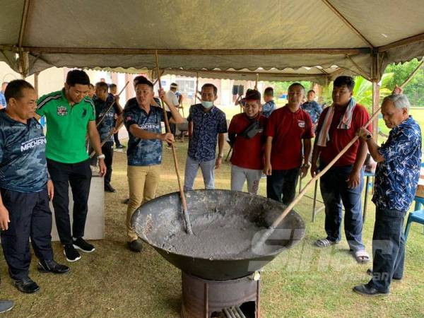 Muhammad Nasir (kanan) tidak melepaskan peluang mengacau bubur asyura pada Majlis Kacha Sugho Peringkat IPD Machang hari ini.