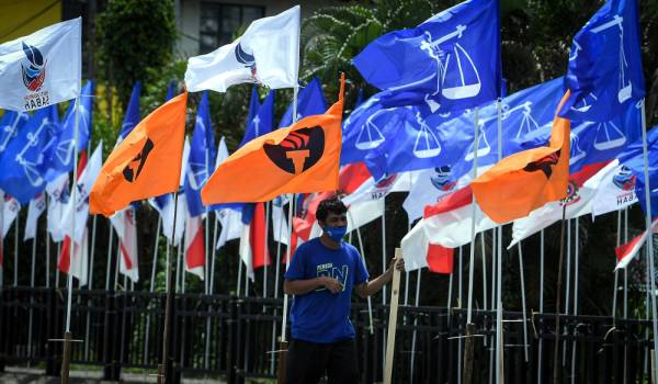 Seorang petugas Barisan Nasional kelihatan menaikkan bendera bagi memeriahkan lagi kehangatan berkempen ketika tinjauan Pilihan Raya Sabah (PRN) di sekitar Jalan Tanjung Aru hari ini. - Foto Bernama