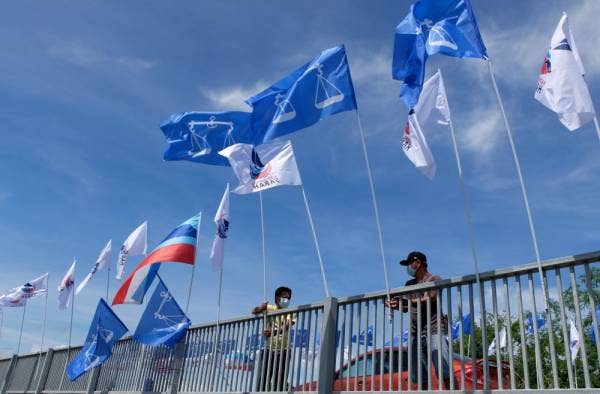 Para petugas Barisan Nasional (BN) menaikkan bendera bagi memeriahkan lagi kehangatan berkempen ketika tinjauan Pilihan Raya Negeri (PRN) Sabah di sekitar Pekan Sipitang. -Foto Bernama