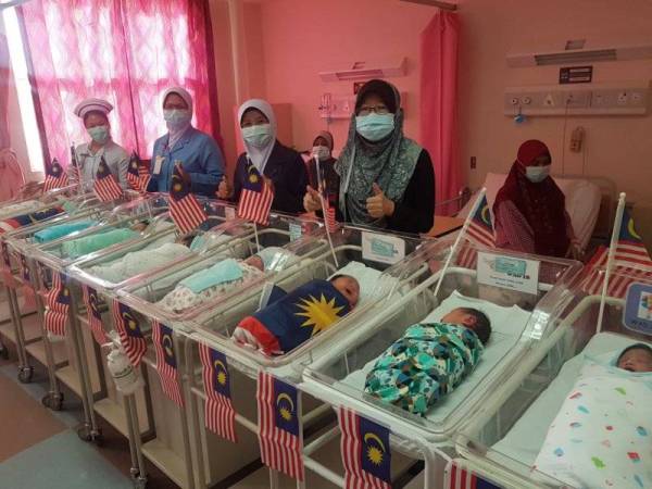 Dr Nora'i Mohd Said (berdiri, kanan) dan Penyelia Jururawatnya, Nor Aziah Ujang (berdiri,dua dari kanan) bergambar bersama 10 daripada 15 bayi 'anak Malaysia' yang dilahirkan di Hospital Putrajaya hari ini.