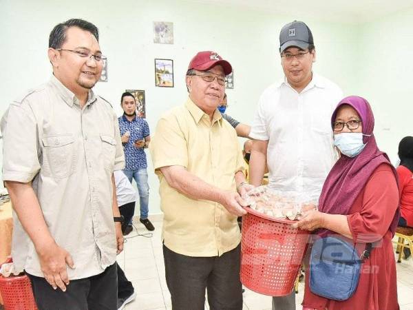Hendry menyampaikan bakul makanan kepada Siti Damit, 60, pada majlis penyerahan tinjauan mesra bakul makanan kepada peserta Felcra di Kampung Ulu Sipitang.