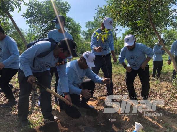 Mohd Sani (duduk) melaksanakan acara penanaman pokok di Rimba Lestari UMP Pekan.