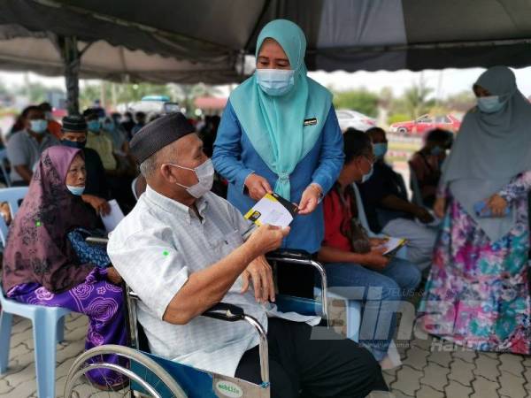 Wan Norashikin menyampaikan Kad Perak Prihatin kepada salah seorang penerima di kawasan Kampung Gajah hari ini.
