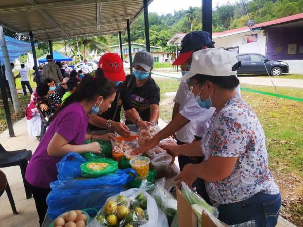 Margaret (kanan) melayan pengunjung yang datang membeli produknya yang dijual di lot gerai Kampung Maang, Penampang. 