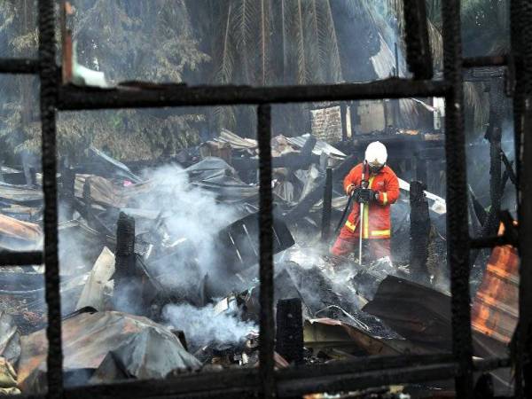 Anggota bomba dan penyelamat memadamkan sisa kebakaran yang memusnahkan rumah Abdul Rahman di Kampung Muanad 3, Beluran hari ini.