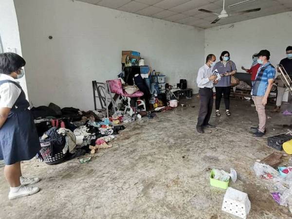 Salah seorang daripada tiga beradik berkenaan menunjukkan keadaan rumah dihuni mereka bersama 13 ekor anjing ketika kunjungan pegawai JKM dan Chon Siang, hari ini.