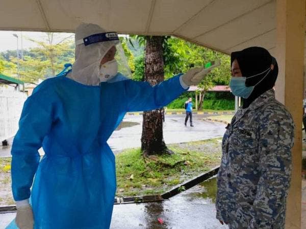 Petugas SPR lengkap berpakaian PPE melakukan pemeriksaan suhu badan pada anggota yang terlibat dalam proses pengundian awal di Sekolah Kebangsaan TLDM Kota Kinabalu pagi ini.