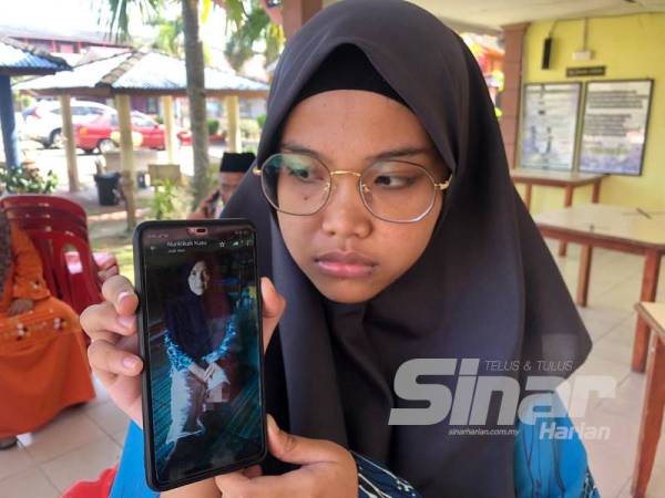 Nor Atikah (kanan) menunjukkan gambar ibunya, Nor Hayati yang kudung kaki kiri akibat penyakit kencing manis kronik.