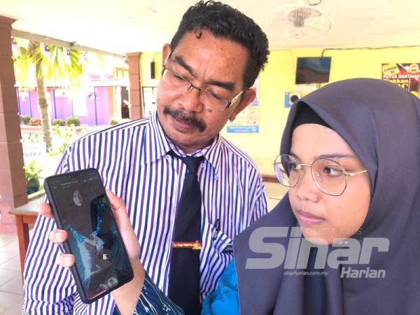 Nor Atikah (kanan) menunjukkan gambar ibunya, Nor Hayati sambil diperhatikan Pengetua, Kamaruddin Hassan.