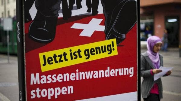 Seorang anggota Parti Rakyat Switzerland dan juga anggota parlimen perbandaran Geneva, Vincent Schaller bergambar di sebelah poster partinya berhubung kehadiran imigran asing di negaranya di Geneva baru-baru ini. - Foto AFP