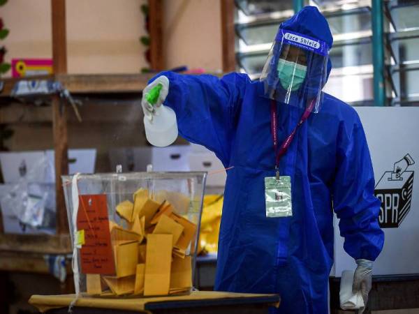 Petugas SPR melakukan pembersihan dan sanitasi ketika tinjauan pada hari pengundian Pilihan Raya Negeri Sabah ke-16 di Sekolah Kebangsaan Pulau Gaya hari ini. - Foto Bernama