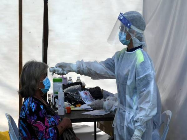 Petugas dari Jabatan Kesihatan melakukan saringan terhadap pengundi yang menunaikan tanggungjawab mengundi di Sekolah Kebangsaan Mantob hari ini. Foto Bernama