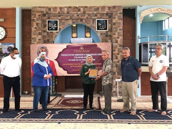 Muhammad Nasir (kanan) menyerahkan Al-Quran kepada Nancy (kiri) di Masjid Darul Iman Sadong Jaya di sini.