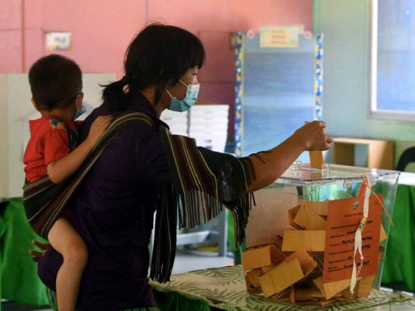 Pengundi Maitah Tandasai mengendong anak kecil semasa mengundi pada Pilihan Raya Negeri Sabah ke-16 di Sekolah Kebangsaan Mantob Sabtu lalu. - Foto Bernama