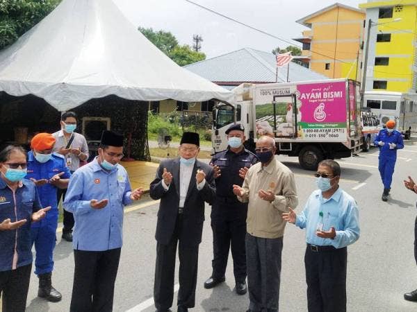 Fadhil (tengah) membacakan doa untuk penduduk dikenakan PKPD secara bersasar pada Majlis Penyerahan Ayam Segar kepada penduduk Flat Tongkang Yard, di sini, hari ini.