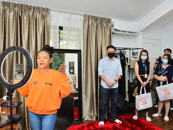 Shu Wei (belakang,kiri) memberi penjelasan tentang penggunaan Mesh Wi-Fi yang berfungsi memberi pengalaman internet lebih stabil dan lancar untuk pengguna merakam video serta menonton drama kegemaran pada masa yang sama