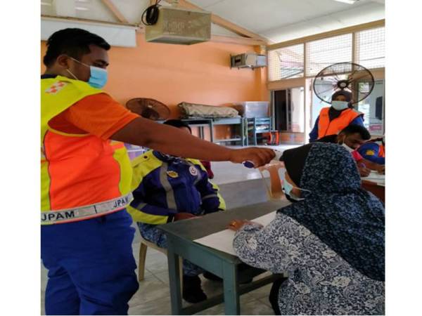 Anggota APM membuat pemeriksaan suhu badan di PPS.
