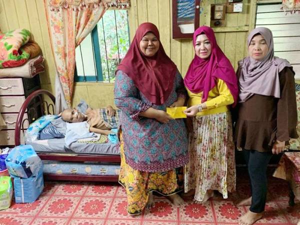 Che Norhayati (tengah) dan Rosnani turut memberikan sumbangan segera kepada Siti Aisyah ketika menziarahi suaminya di Kampung Kedai Buloh di sini.