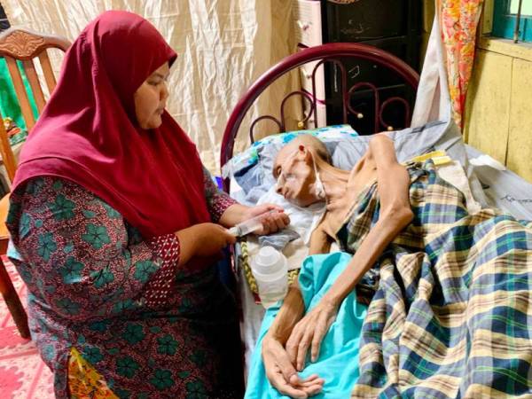 Siti Aisyah memberikan air kepada suami tercintanya yang terlantar menggunakan tiub.