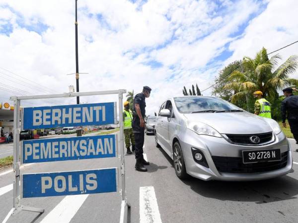 Anggota polis membuat sekatan jalanraya di Jalan Sabindo-Papar berikutan perintah larangan rentas daerah bagi mengelak penularan COVID-19 ketika tinjauan hari ini. - Foto Bernama