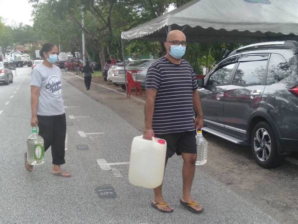 Bhupinder (kanan) bersama ibunya, Kalwant Kour,64, mengangkat tong bekalan air yang diambil di PKS USJ4/5, hari ini.