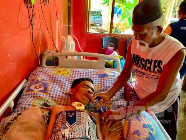 Ismail memberikan air meneral kepada anaknya, Mohd Suhaimi yang terlantar akibat strok.