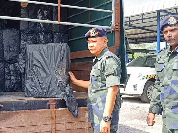 Ku Majidin (kiri) menunjukkan lori yang sarat dengan muatan rokok seludup dipercayai untuk pasaran tempatan.