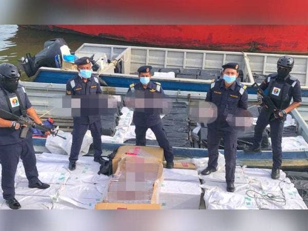 Muhd Nur Syam Asmawie (tengah) menunjukkan rokok dan bot berkuasa tinggi yang dirampas selepas mematahkan cubaan menyeludup 200 bungkusan rokok putih bernilai RM1.49 juta.