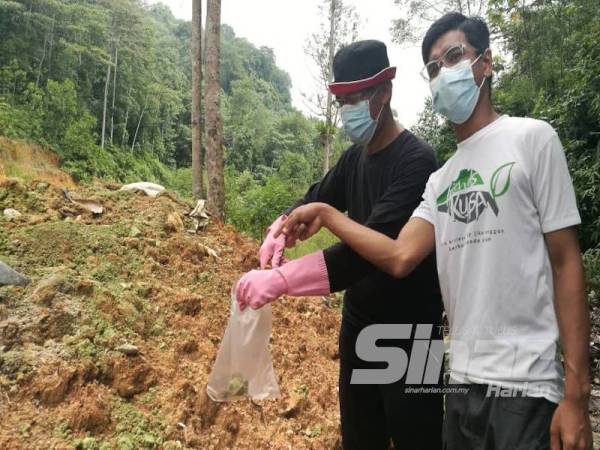 Meor Razak (kiri) mengambil sampel bahan berwarna hijau sambil diperhatikan aktivis SAM, Muhammad Izzat Nasaruddin, 18, di kawasan berhampiran Resort D'Lereng hari ini.