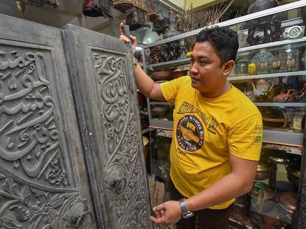 Mohamad Fauzi memeriksa pintu rumah lama yang dikumpulnya. -Foto Bernama