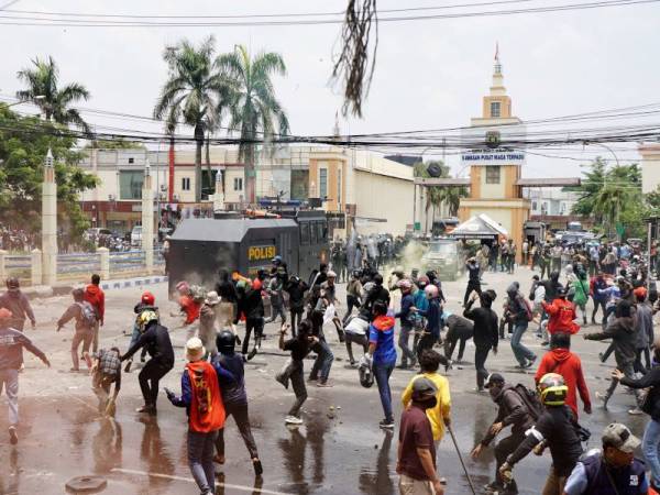 Peserta protes membaling batu bata dan serpihan konkrit kepada anggota keselamatan di Tangerang. - Foto AFP