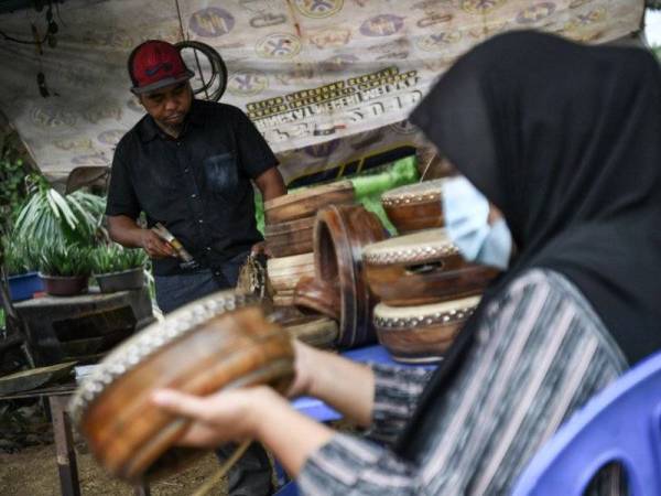 Kassim bersama isterinya, Siti Suhaila Shamsuddin melakukan kerja-kerja penukangan rebana. -Foto Bernama