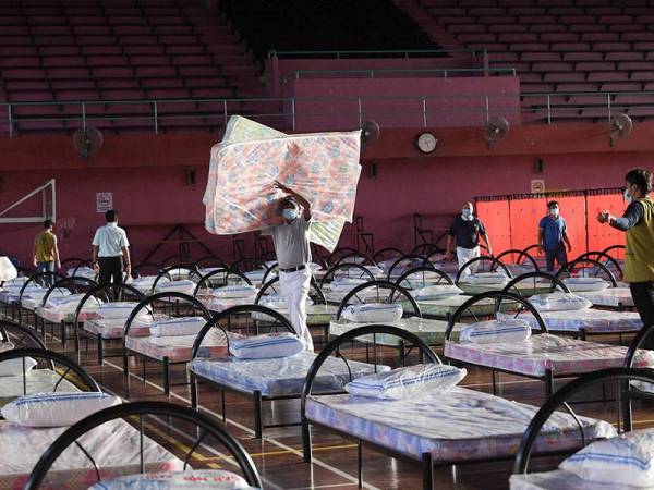 Seorang petugas mengangkat tilam untuk kegunaan pesakit COVID-19 yang stabil di Kompleks Sukan Sandakan yang akan dijadikan pusat rawatan berikutan peningkatan jumlah jangkitan di daerah tersebut hari ini.