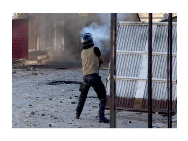 Seorang anggota pasukan keselamatan melepaskan tembakan gas pemedih mata ke arah para penunjuk perasaan di bandar Sbeitla semalam. - Foto AFP