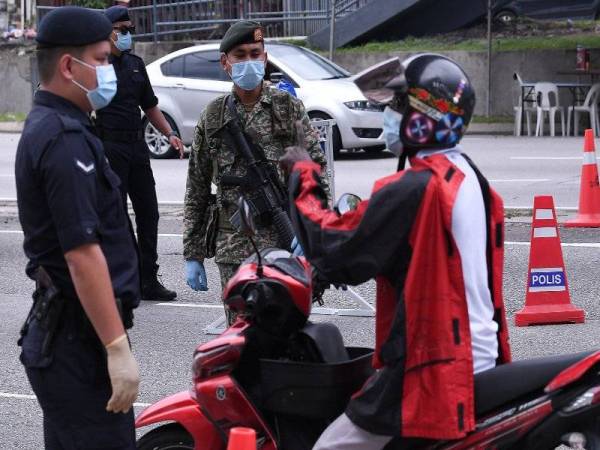 Anggota PDRM dan ATM memeriksa pengguna motosikal yang melalui sekatan jalan raya PKPB yang dilaksanakan bermula hari ini ketika tinjauan di Jalan Kuching, hari ini. Foto: Bernama