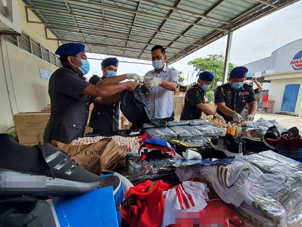 Mohd Ridzuan (tengah) bersama pegawainya melakukan proses pelupusan barangan tiruan Kompleks Penyimpanan Ekshibit KPDNHEP di Bukit Minyak, Bukit Mertajam hari ini.