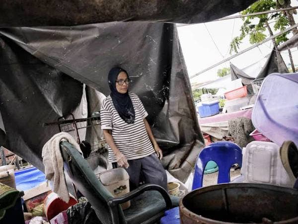 Tianti meninjau bahagian dapur rumahnya yang berselerak selepas kejadian ribut semalam menerbangkan zink bahagian dapur di Kampung Pasir Putih, Putatan.