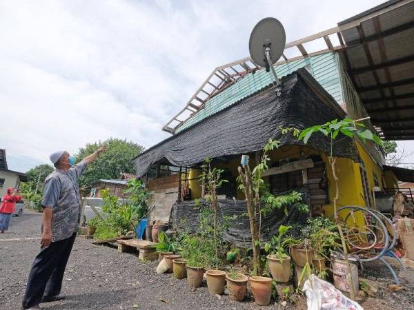 Ridzuan melihat rumah penduduk yang rosak kerana ribut malam tadi.